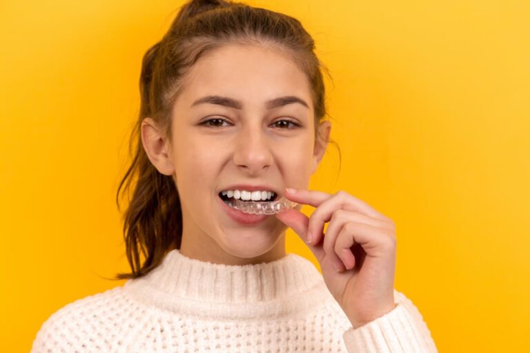Young woman wearing turtle neck, holding clear aligners in her mouth
