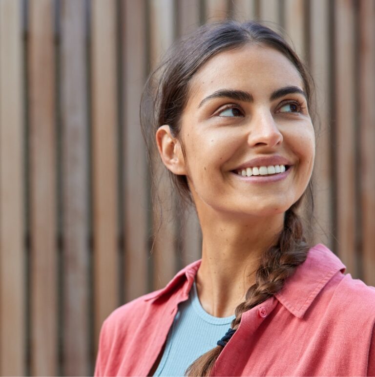 Adult woman smiling outside while wearing Invisalign clear aligners