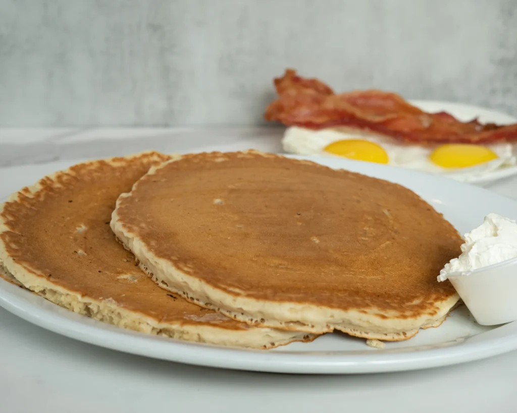 a plate of pancakes, bacon, and eggs