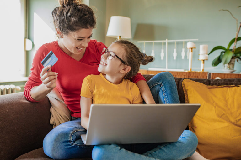 Mother and daughter on the couch on a laptop with credit card, Use your FSA for braces or clear aligners, Premiere Orthodontics in Orlando