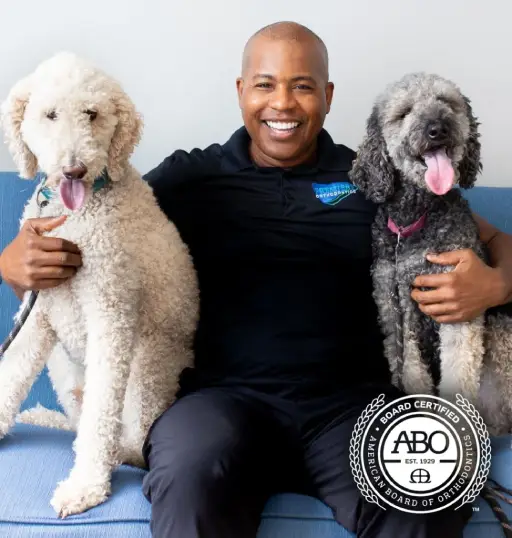 Dr. Jason Battle, board-certified orthodontist in Orlando, with two dogs, showcasing Premiere Orthodontics care.